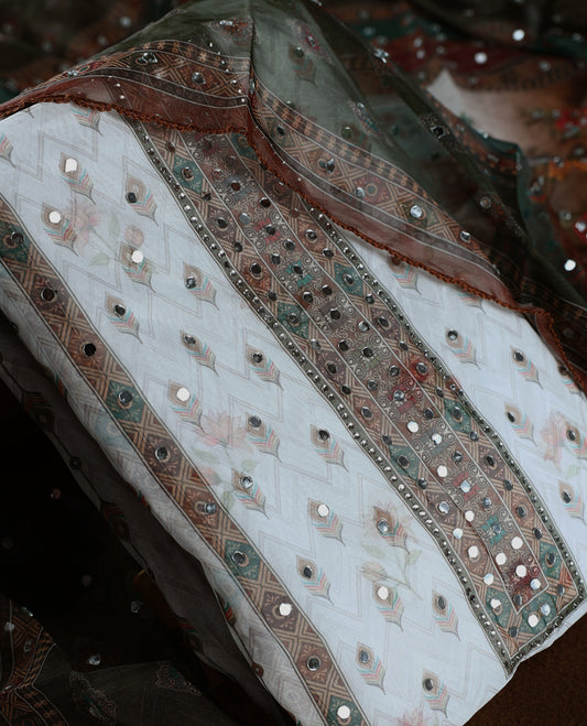 Elegant white churidhar material adorned with mirror work and subtle floral prints, enhanced by a rich green brown printed dupatta with sequin highlights, paired with a plain white bottom for a classy festive look.