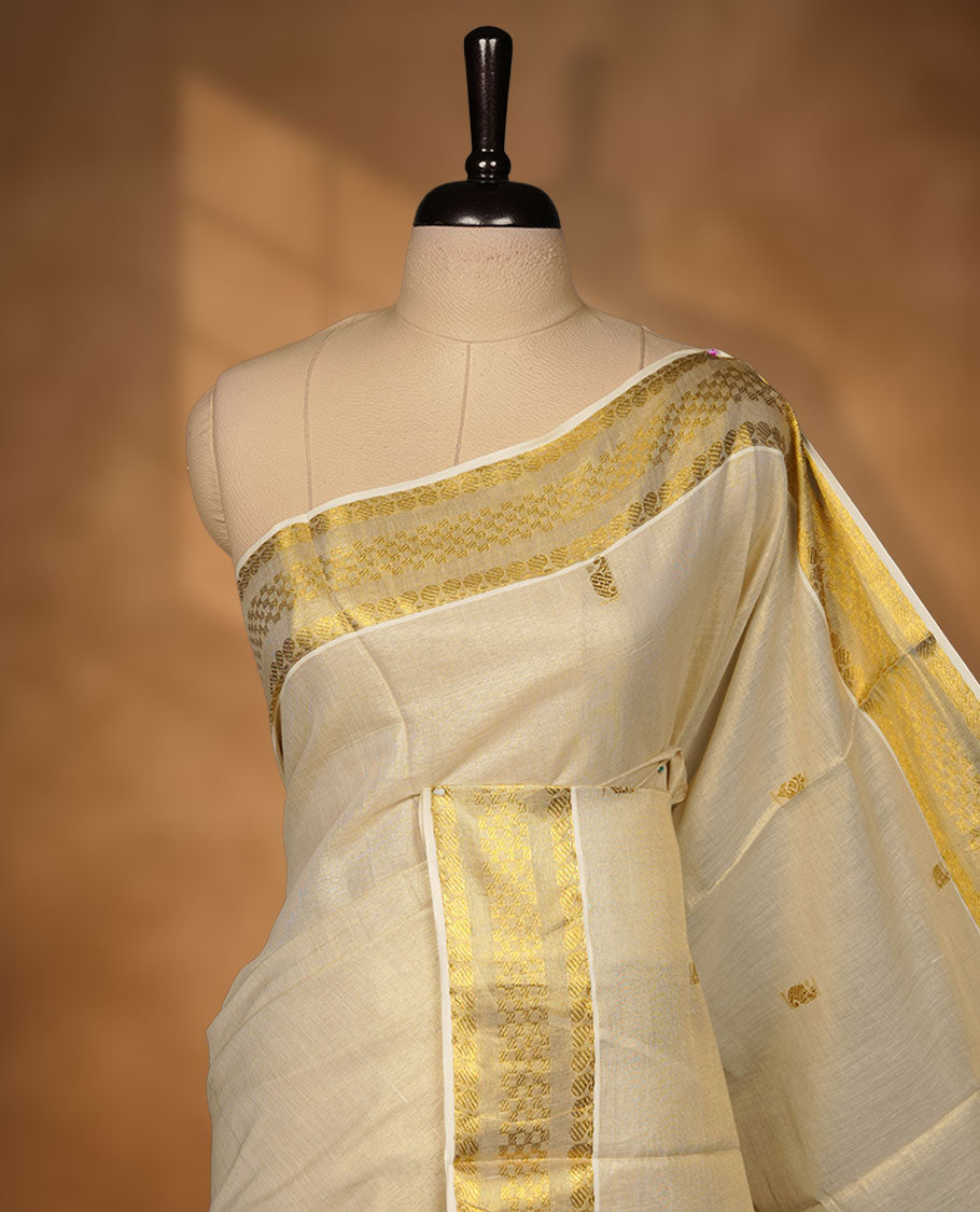 off-white Kerala saree crafted in soft tissue fabric, featuring subtle gold zari buttas across the body, a richly woven traditional pallu with intricate motifs, and a classic kasavu border, paired with a matching blouse.