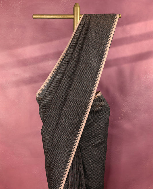 Black colour pure linen saree featuring fine beige thread stripes running throughout the body, accented with a soft beige border and pairs gracefully with a matching blouse.