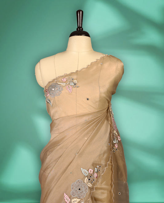 Dusty Pastel Brown colour organza saree featuring delicate floral embroidery with applique bead, mirror, and thread detailing on the body and scalloped border, lending a soft feminine charm, paired with a matching blouse.