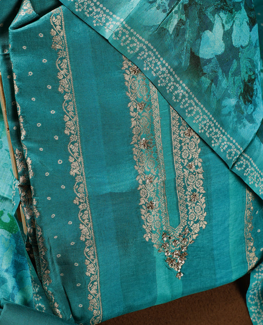 Teal green colour churidhar material adorned with intricate zari embroidery on the neckline, paired with a plain matching bottom and a floral printed dupatta highlighted with dotted accents.