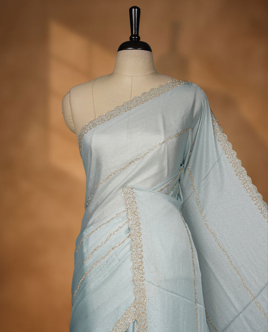 Powder Blue colour net shimmer fancy saree with a plain body, paired with a delicate stone worked border, with matching blouse