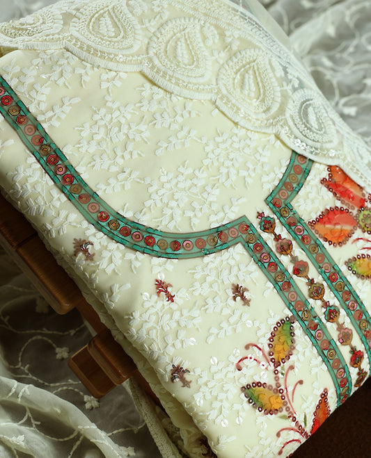 Cream colour churidhar material with embroidered green colour neck work, white thread floral motifs on the body, and multicolor floral detailing in orange, yellow & green, Comes with plain bottom and embroidered dupatta.