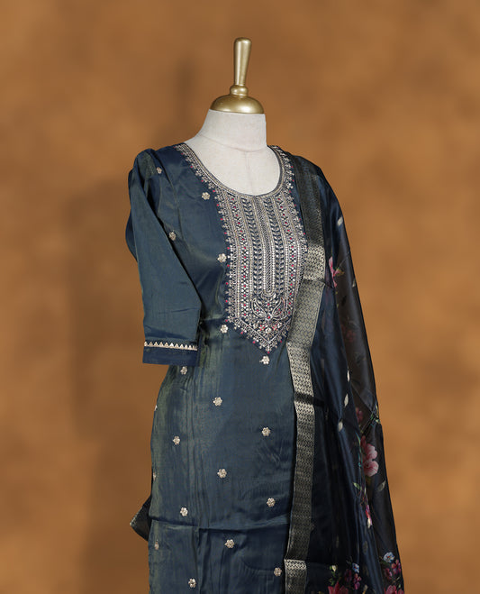 Dark grey blue churidar set featuring round neckline, elbow sleeves, and intricate embroidered yoke with scattered buttis, paired with a sheer floral printed dupatta.