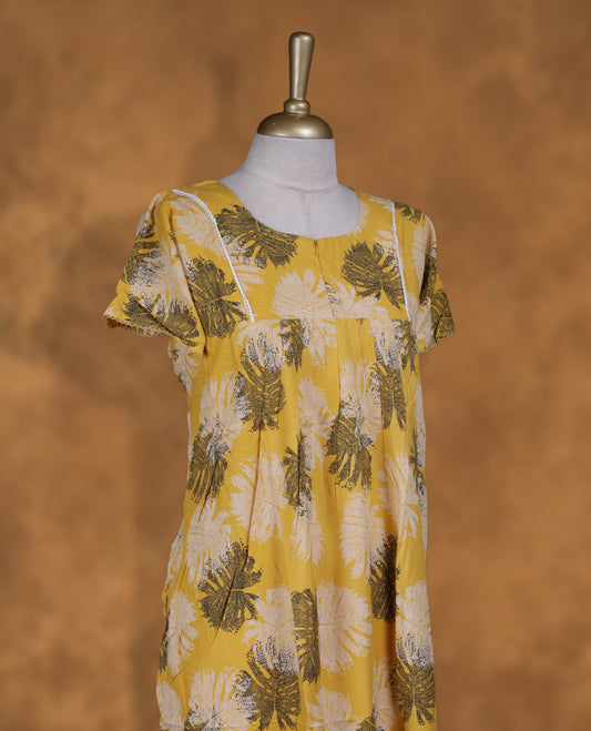 Yellow colour NStyle nighty featuring black and white leaf patterns, a round neckline with gathered detailing, short sleeves, and a full ankle-length design.
