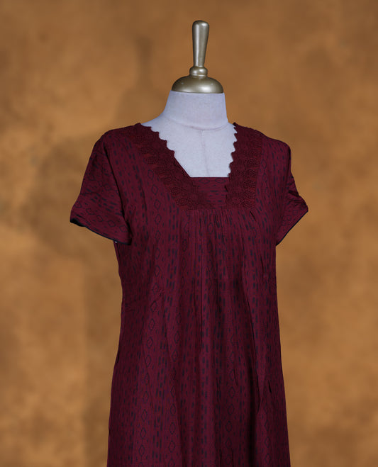 Dark red colour NStyle nighty featuring black patterns, a V-neckline with thread lace detailing, short sleeves, and a full ankle-length design.