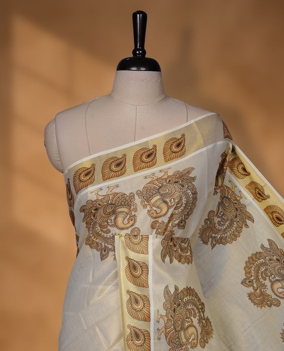 Off-white colour tissue Kerala saree with an elegant gold kasavu border, adorned with antique gold peacock and paisley motifs across the body and pallu, paired with a matching blouse.