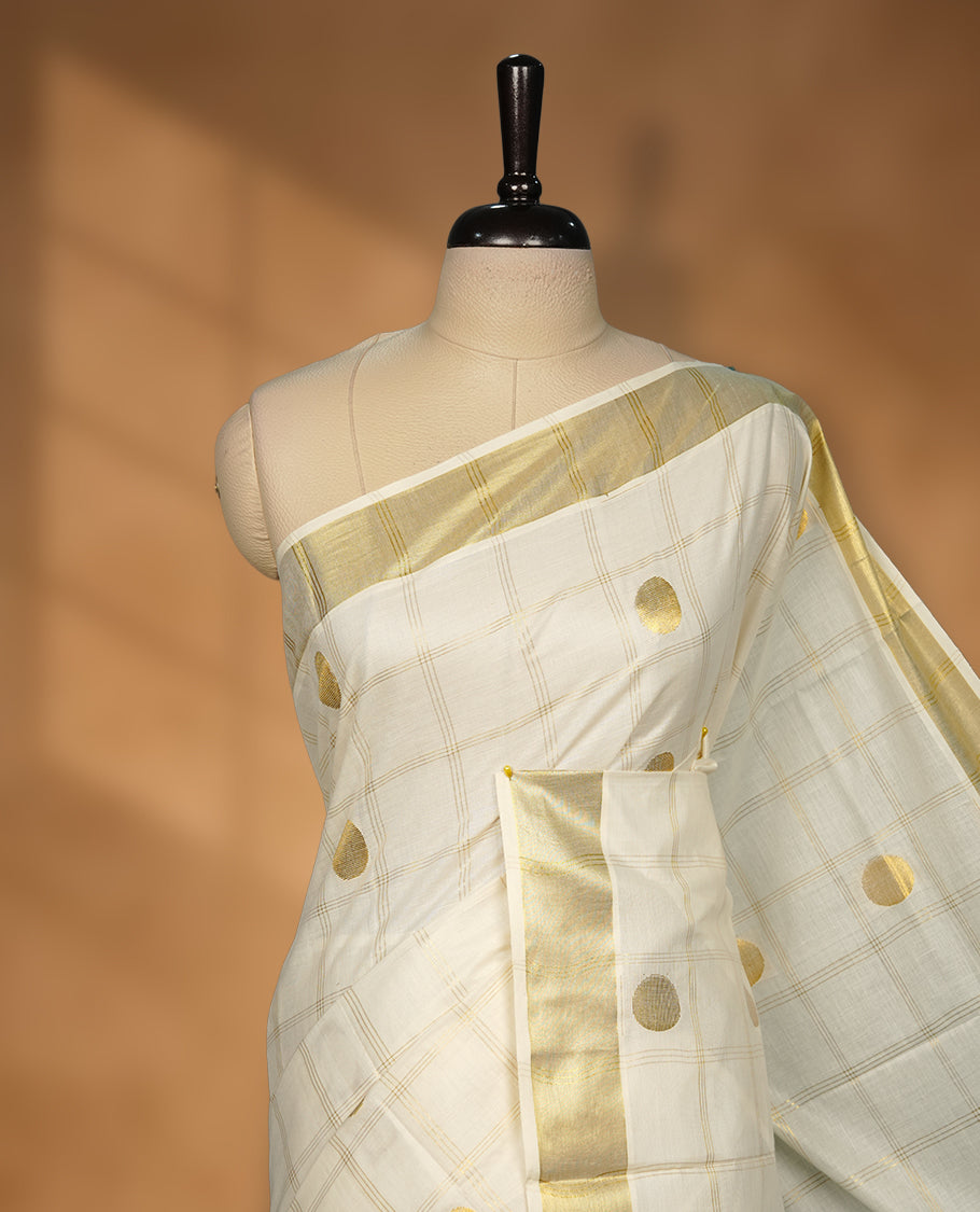 Elegant Off white colour cotton Kerala saree with gold zari check stripes and buttas, broad kasavu border, and richly woven traditional pallu, paired with a matching blouse