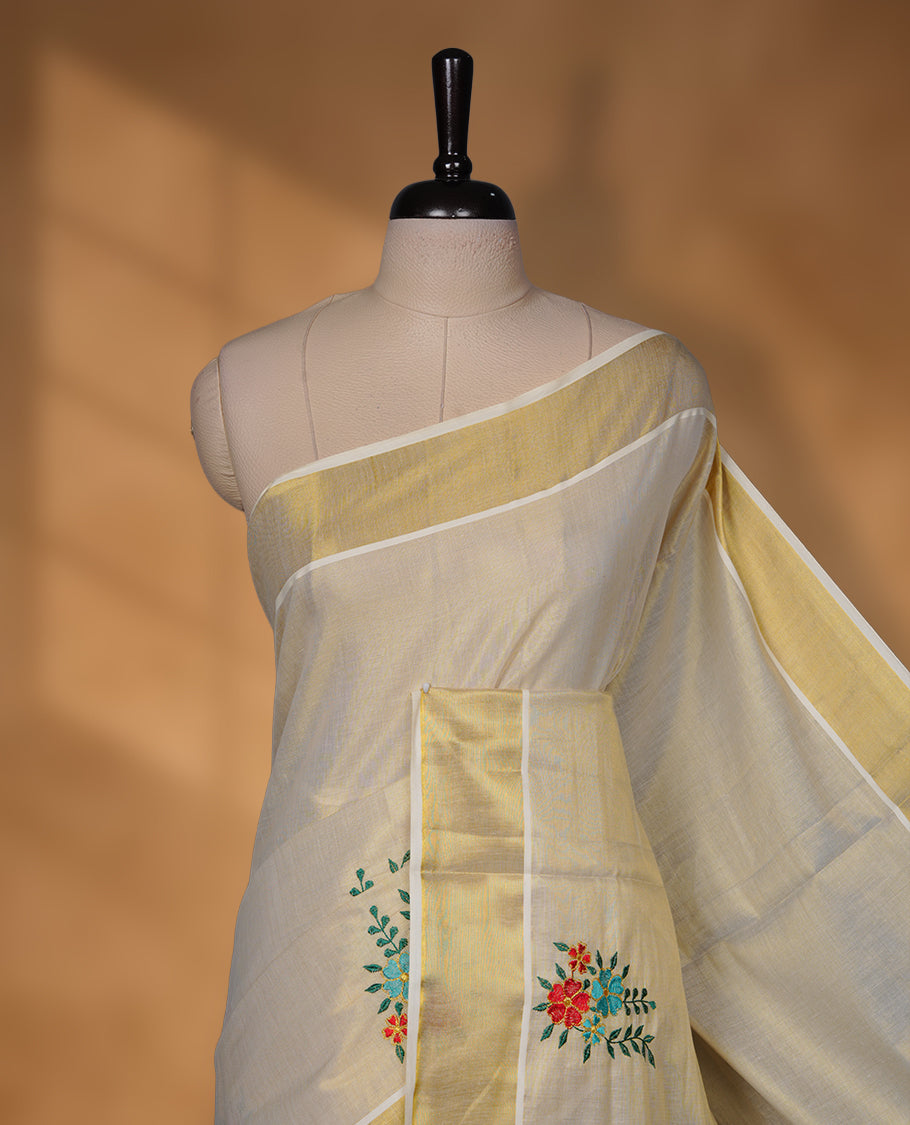 Off-white Kerala kasavu saree with delicate floral embroidery, finished with a classic gold border and paired with a matching blouse.