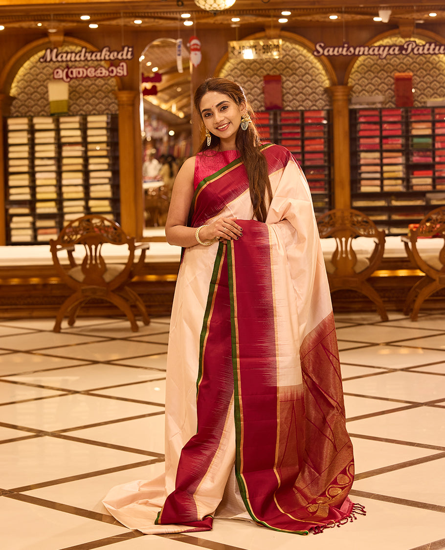 Ivory colour pure kancheepuram silk saree featuring a rich gold zari temple pallu, complemented with a contrast deep red border finished with gold and green selvedge and a matching deep red pallu, beautifully paired with a matching blouse.