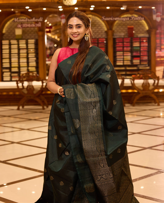 Bottle green pure Mayuri Soft silk saree adorned with elegant antique zari motifs across the body, featuring a traditional antique zari pallu and a refined one side border, gracefully paired with a matching blouse