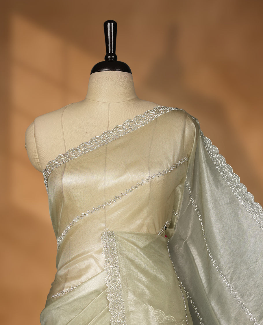 Pastel olive Colour net shimmer fancy saree adorned with strip white stone buttas all over the body, paired with a delicate stone worked border and matching blouse