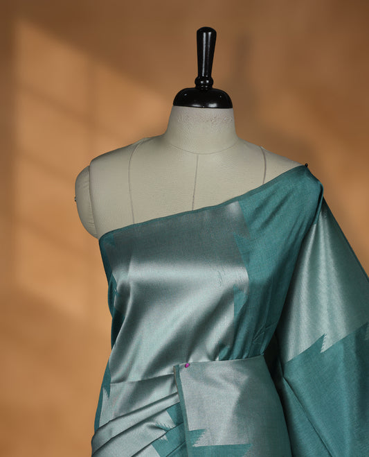 Green and silver dual tone colour semi tussar saree featuring woven abstract geometric motifs on the body, complemented by a ikat inspired patterned pallu, paired with a matching blouse.