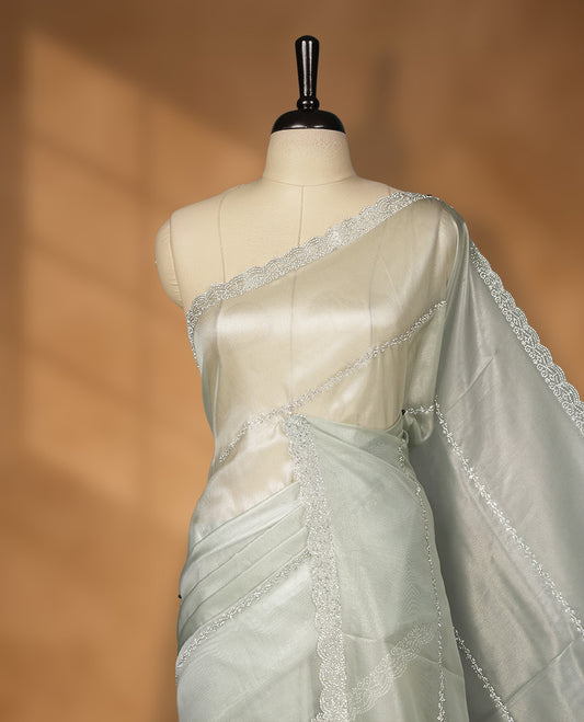 Ash Green Colour net shimmer fancy saree adorned with strip white stone buttas all over the body, paired with a delicate stone worked border and matching blouse