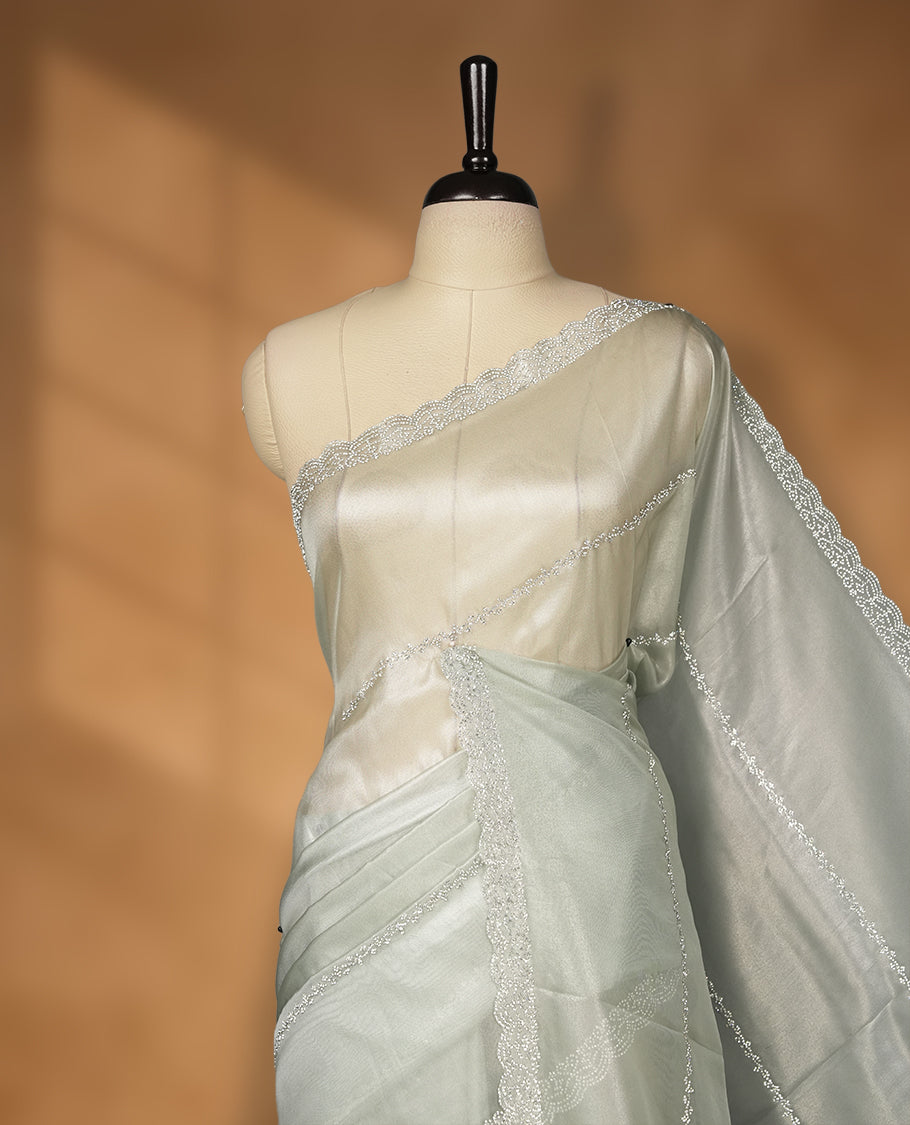 Ash Green Colour net shimmer fancy saree adorned with strip white stone buttas all over the body, paired with a delicate stone worked border and matching blouse