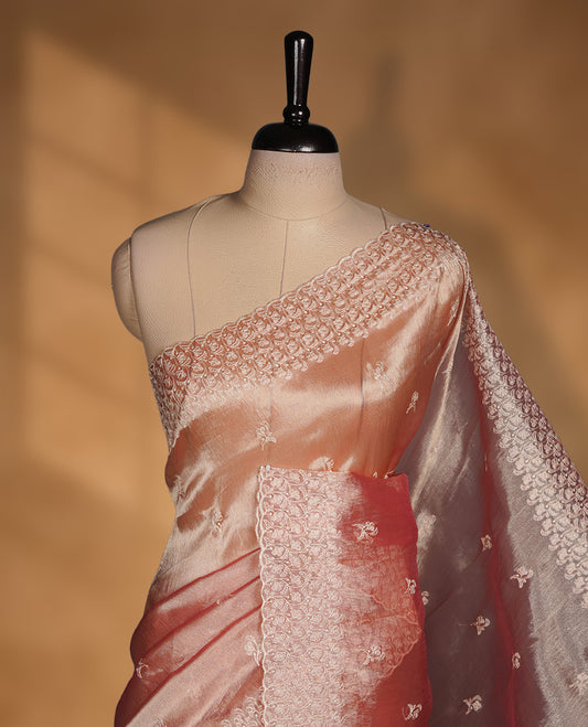 Pastel peach colour organza saree featuring white thread embroidery motifs on body and  thread detailing on the border and paired matching blouse.