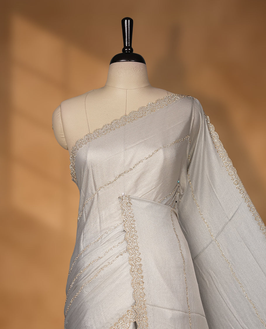 Gray silver Colour net shimmer fancy saree adorned with strip gold stone buttas all over the body, paired with a delicate stone worked border and matching blouse