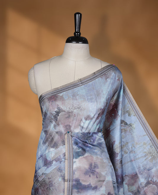 Smoky grey colour semi tussar silk saree featuring an abstract digital floral printed body, finished with a rich self border and tasselled pallu, paired with a matching blouse.