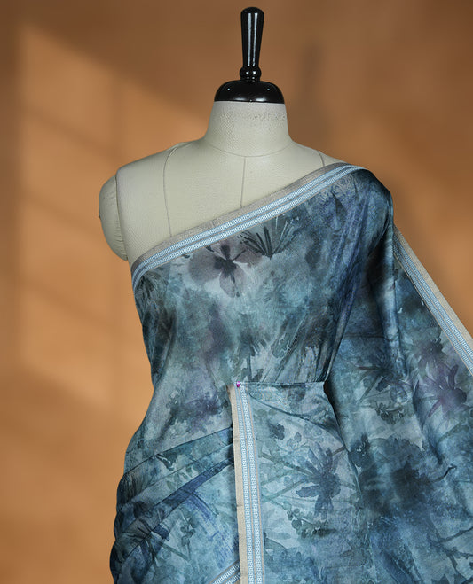 Dark Green colour semi tussar silk saree featuring an abstract floral printed body with a rich self border and tasselled pallu, paired with a matching blouse.