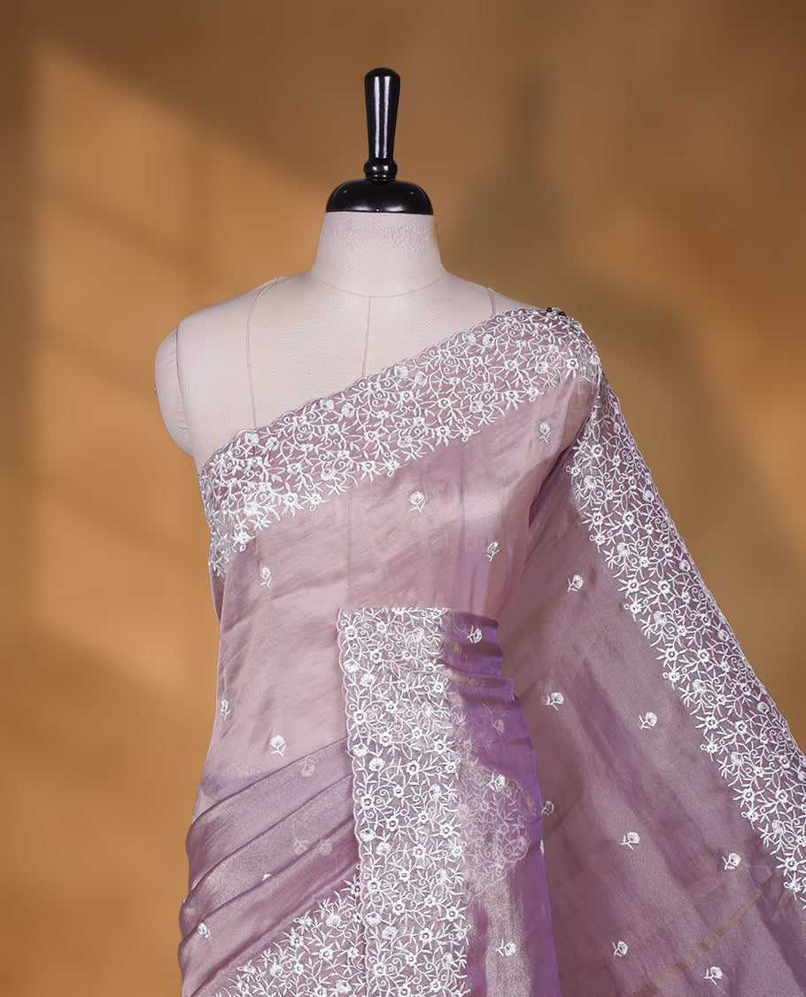 Light purple colour net organza designer saree featuring a subtle self patterned body and an intricately scalloped floral thread embroidered border all around, complemented by a coordinating embroidered pallu and paired with a matching blouse.