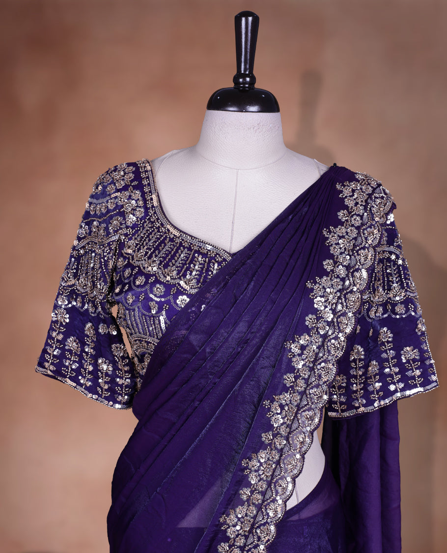 Elegant deep purple colour ready to wear saree adorned with rich gold bead embroidery along the border and pallu, paired with a heavily embellished matching blouse for a grand festive look.