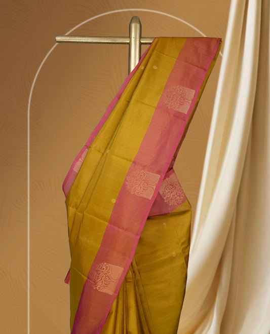 Mustard yellow colour soft silk saree highlighted with a rich contrast pink border adorned with elegant zari motifs & Paired with a matching blouse.