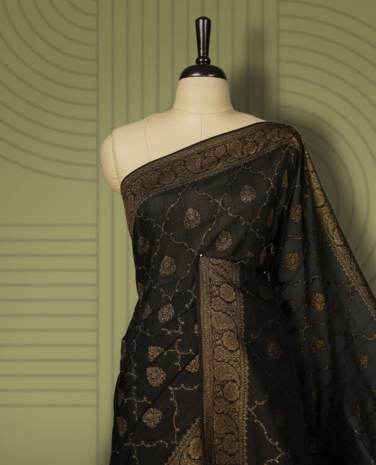 Black colour semi Banarasi Tussar Georgette saree with gold zari motifs on the body, a grand woven golden pallu, and ornate zari border, Includes a matching blouse piece for a complete look.