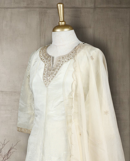 Beige colour salwar from TWARA, featuring a delicate embroidered neck with floral thread work, all over golden style embroidery on the top, paired with a matching bottom and an elegant dupatta.