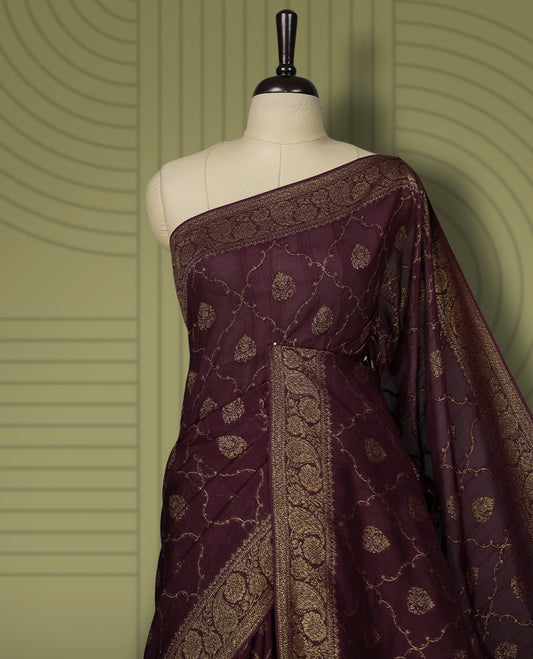 Dark maroon colour semi Banarasi Tussar Georgette saree with gold zari motifs on the body, a grand woven golden pallu, and ornate zari border. Includes a matching blouse piece for a complete look.