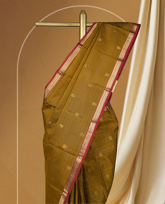 Dusty mustard yellow soft silk saree enhanced with delicate zari buttas, paired with a striking rust orange zari border and elegant pallu & Comes with a matching blouse.