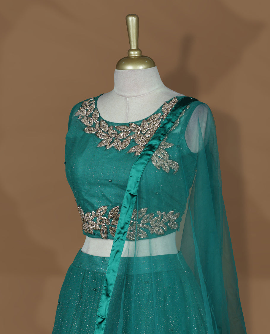 Teal green colour lehenga set with stitched sleeveless blouse featuring floral sequin embroidery on neckline and waist, paired with a matching shimmer layered flared lehenga and sheer dupatta