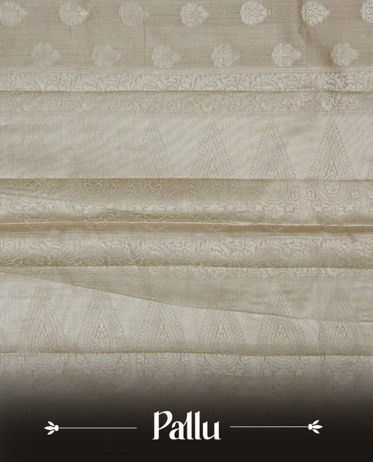 Beige colour Banaras saree featuring Silver zari buttas on body, complemented by zari pattern on self colour border, comes with matching blouse piece.
