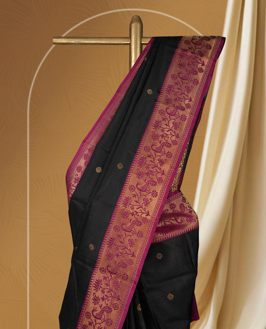 Black colour soft silk saree adorned with golden buttas, enhanced by a deep magenta border and pallu featuring intricate zari floral designs & Paired with a matching blouse.