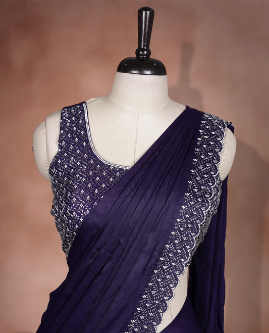 Elegant deep purple colour ready to wear saree adorned with rich white stone and bead embroidery along the border and pallu, paired with a heavily embellished matching blouse for a grand festive look.