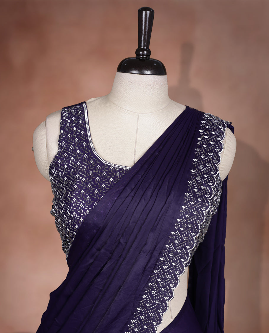 Elegant deep purple colour ready to wear saree adorned with rich white stone and bead embroidery along the border and pallu, paired with a heavily embellished matching blouse for a grand festive look.