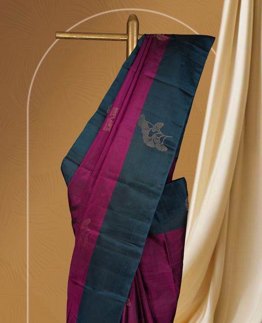 Dark magenta colour soft silk saree adorned with golden zari motifs, enhanced by a deep peacock zari border and pallu with delicate detailing & paired with a matching blouse.