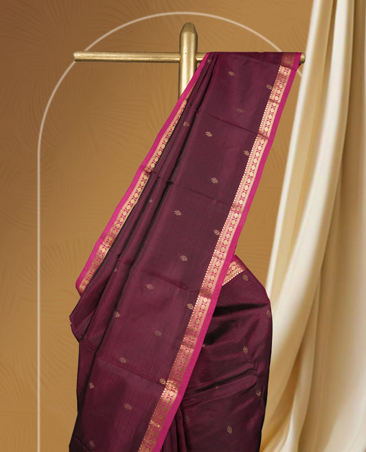 Dark maroon colour soft silk saree with subtle golden buttas, accentuated by a pink zari border and pallu & Paired with a matching blouse.