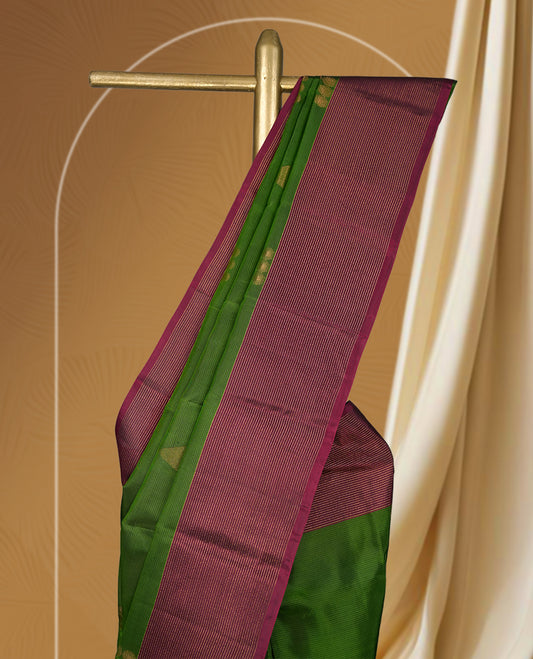 Green colour soft silk saree adorned with minimal golden motifs, paired with a contrasting maroon border and pallu featuring elegant zari patterns & Comes with a matching blouse.