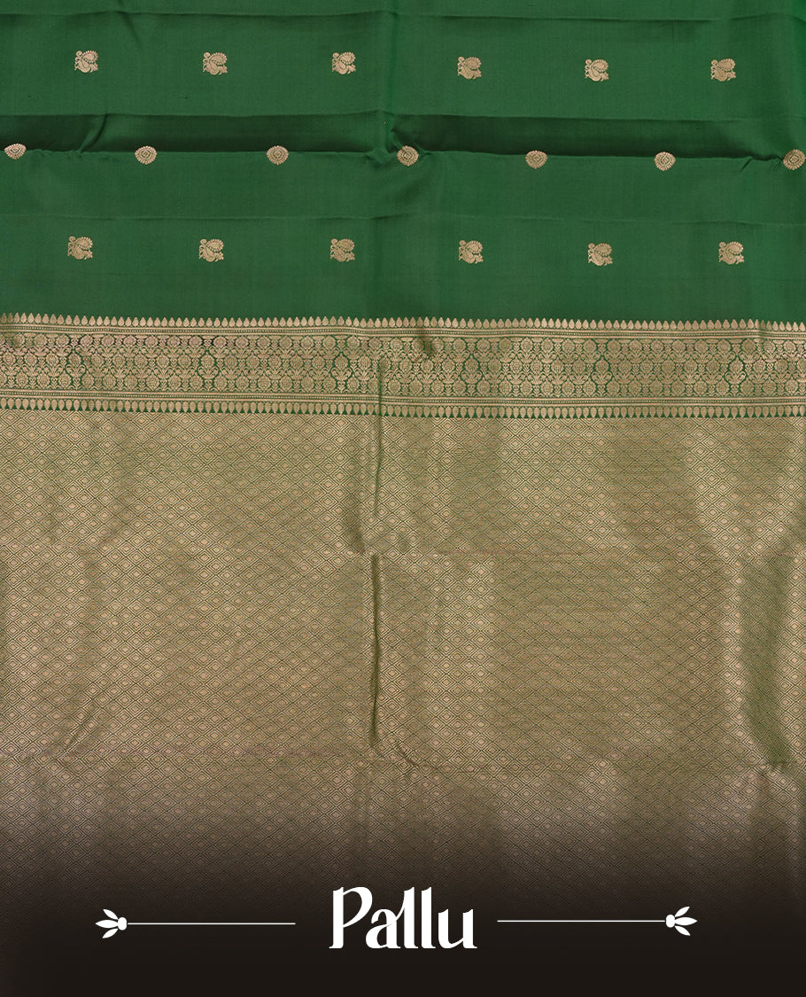 Dark Green colour Vasundhara silk saree adorned with all-over gold chakkaram & mayil motifs on the body, complemented by a gold tarditional border and paired with a matching blouse piece.