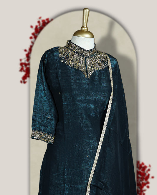 Deep blue colour churidar set with a rich sheen, beautifully adorned with golden cut beads work on the neckline and sleeve borders, Paired with a matching dupatta featuring a subtle zari edge, perfect for a regal festive look.