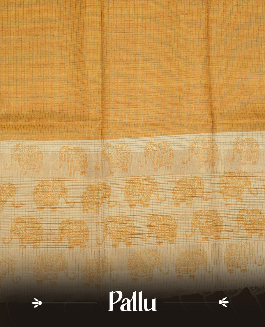 Golden yellow colour semi tussar silk saree featuring an all-over elephant motif print across the body, complemented by a contrasting pallu and border, and paired with a matching blouse piece.