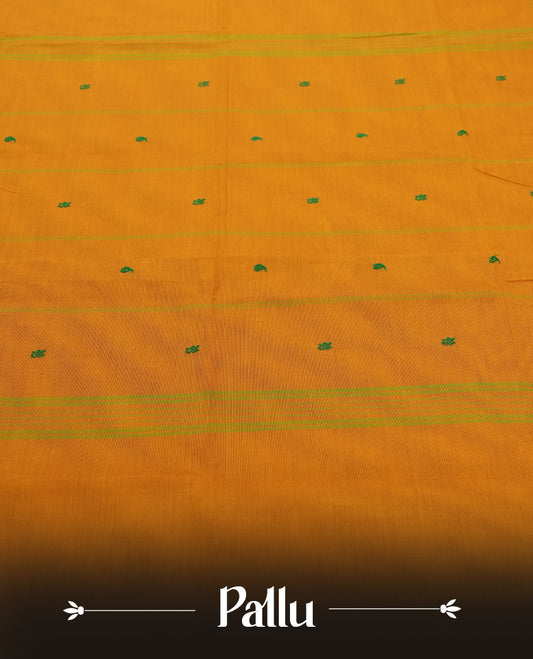 Burnt Mustard Colour silk cotton saree with tiny emerald thread buttas, temple green serrated borders, a pallu lined with green stripes, paired with a plain burnt mustard blouse featuring the same temple green border