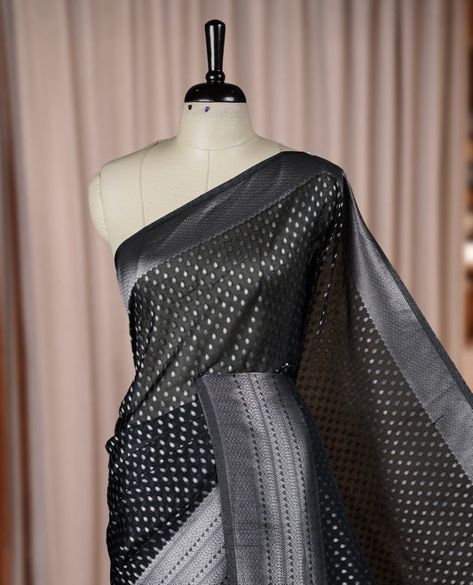 Black colour Banarasi silk saree featuring intricate zari weaving and a soft silk texture, Adorned with silver motifs on the body, complemented by a rich Banarasi border and pallu & Comes with a matching blouse.