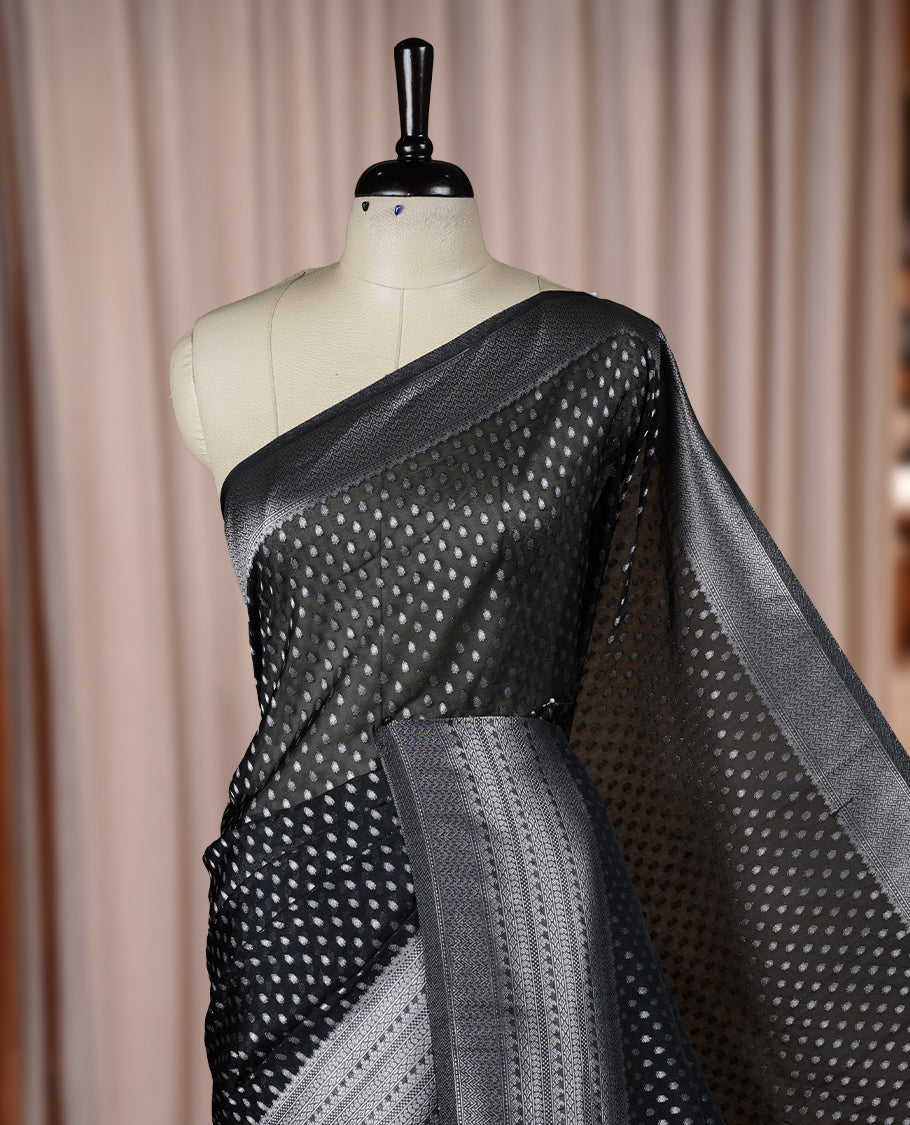 Black colour Banarasi silk saree featuring intricate zari weaving and a soft silk texture, Adorned with silver motifs on the body, complemented by a rich Banarasi border and pallu & Comes with a matching blouse.
