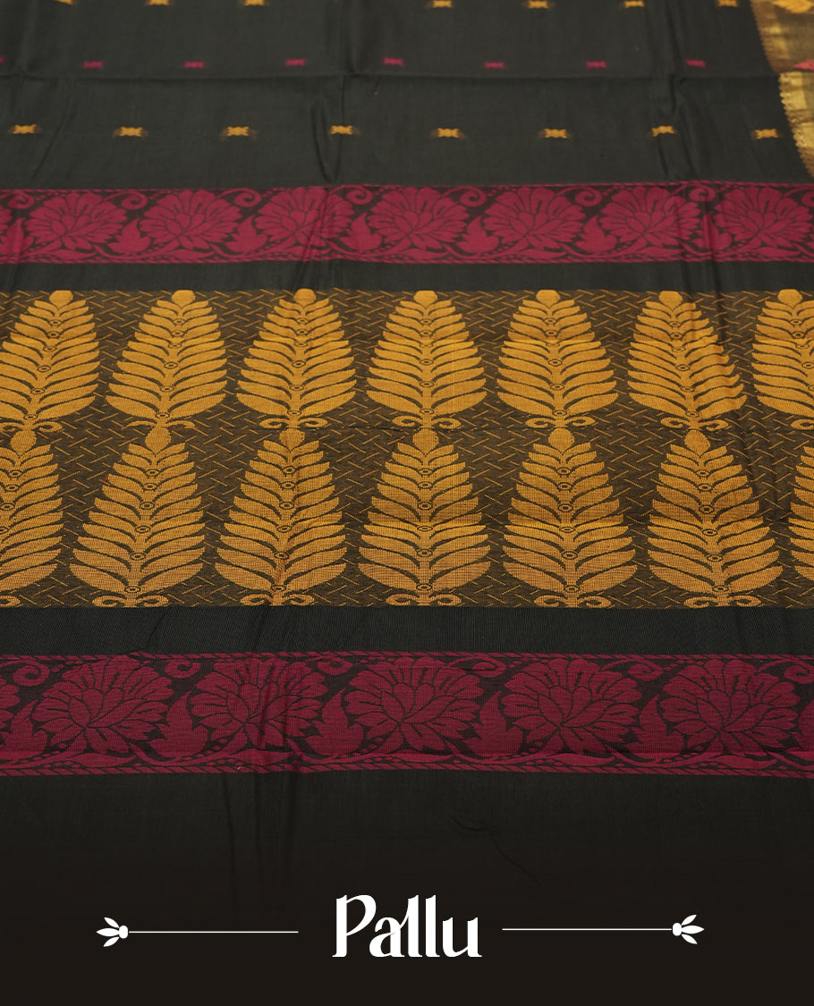 Black Colour silk cotton saree with scattered pink and orange buttas, gold and bronze temple border with pink floral band, gold zari pallu with leaf patterns, black blouse with bronze border.