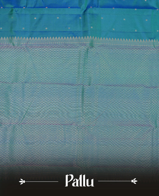 Teal colour Vasundhara silk saree adorned with all-over silver square motifs on the body, complemented by a green & blue box pattern border and paired with a matching blouse piece.