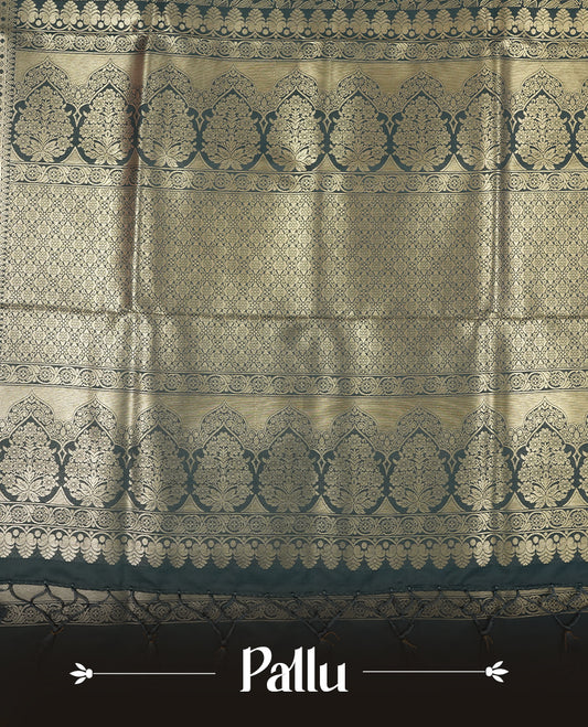 Dark Teal Green colour semi soft silk saree featuring an all-over woven leaf pattern in gold colour, finished with a matching border adorned with detailed paisley and floral motifs, and a matching blouse piece.