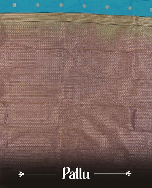 Teal Blue Colour Semi Silk Saree with Golden Peacock Butta Motifs, Contrasting Purple Golden Zari Pallu & Border, Traditional Leaf Designs, and Matching Blouse Piece