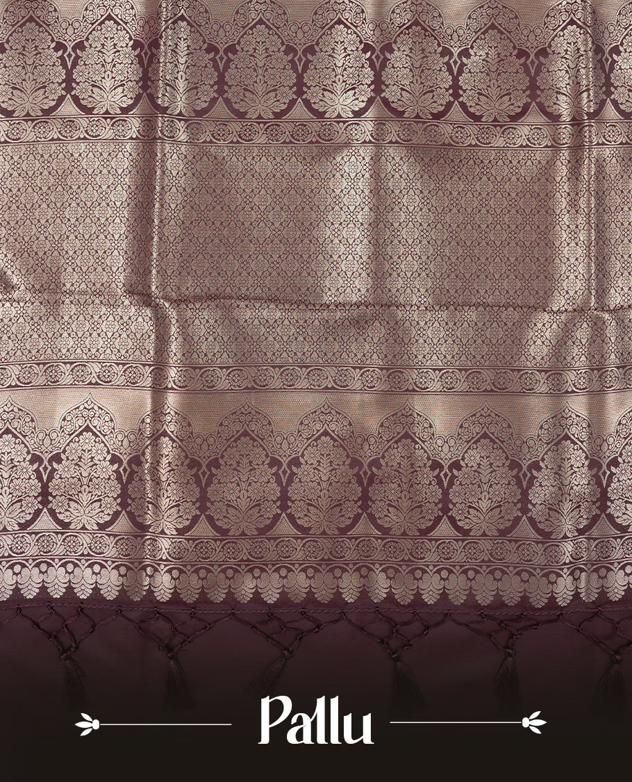 Dark Brown colour semi soft silk saree featuring an all-over woven leaf pattern in gold colour, finished with a matching border adorned with detailed paisley and floral motifs, and a matching blouse piece.