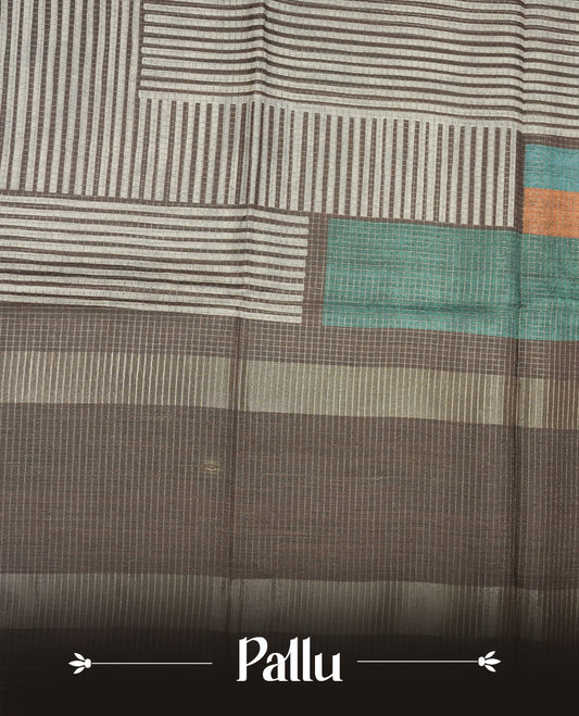 Charcoal Brown colour semi tussar silk saree crafted in breathable cotton, featuring subtle striped textures across the body, a minimalist pallu with fine linear detailing, and a coordinated plain blouse piece.